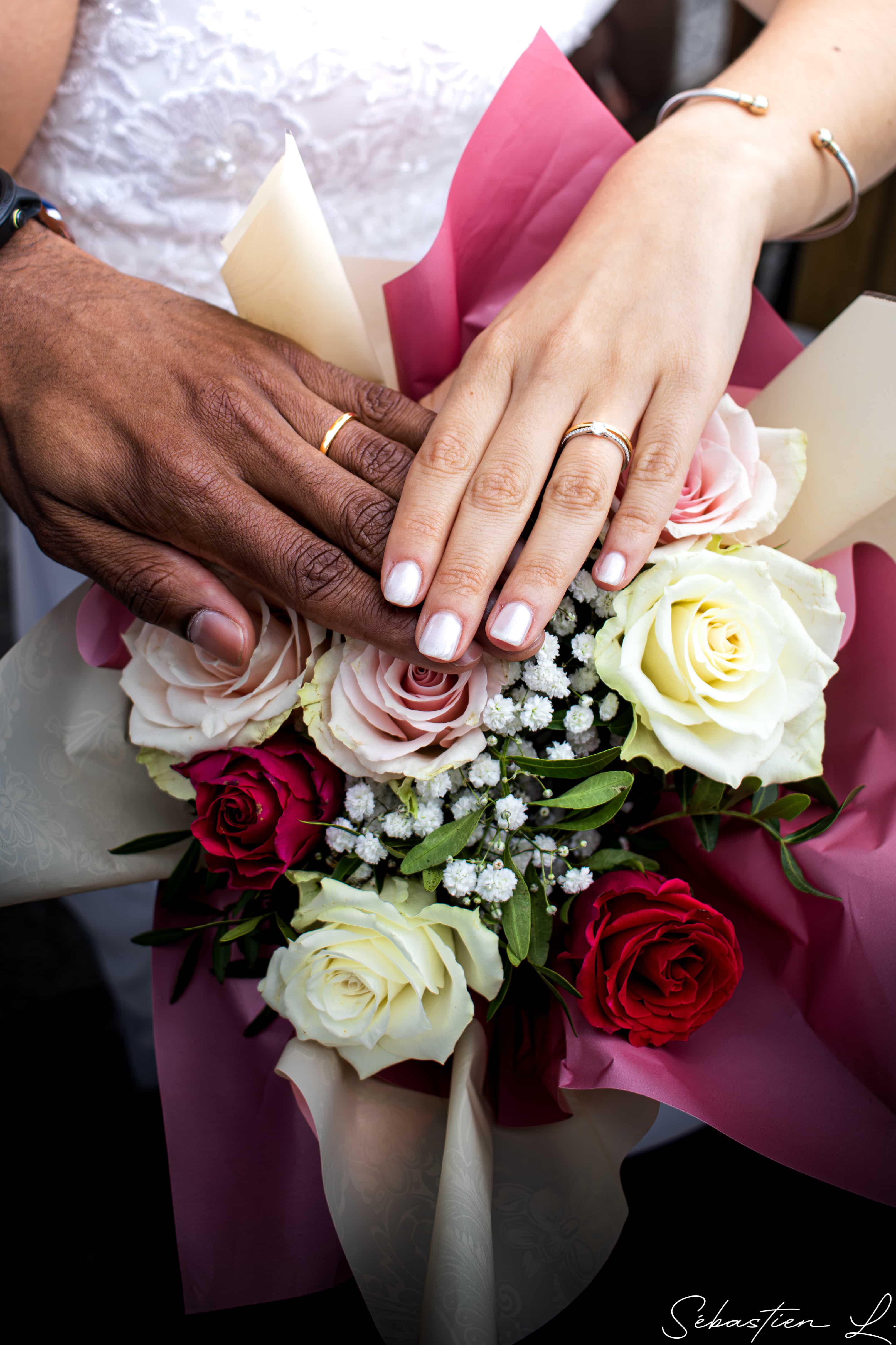 Mains des maries avec alliances au dessus dun bouquet de roses Mains des maries avec alliances au dessus dun bouquet de roses